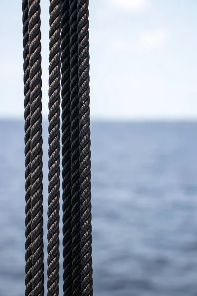 黒い編組ロープと青い水の背景 — ストック写真