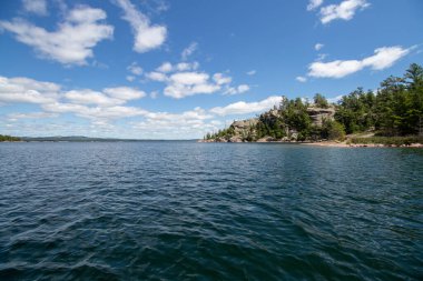 Kuzey Kanalı 'ndaki Ontario, Kanada' daki Benjamin Adaları 'nda mavi gökyüzü ve kuytu bir yaz gününde kayalık bir noktada çam ağaçları.