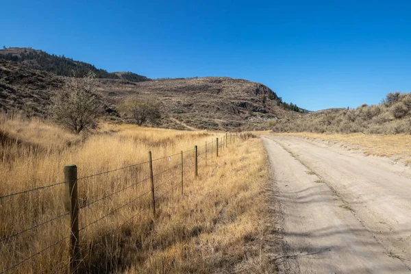 Kanada 'da güneşli bir günde Osoyoos, British Columbia' daki dağlarda tek şeritli toprak yol