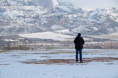 Osoyoos, BC, Kanada - 5 Şubat 2022: British Columbia, Kanada 'da bir kış günü insansız hava aracı uçuran adam