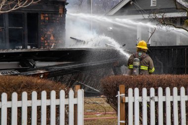 Penticton, BC, Kanada - 7 Mart 2022: Yanan bir eve su püskürten bir itfaiyeci