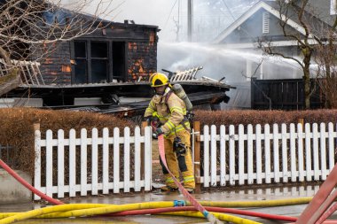 Penticton, BC, Kanada - 7 Mart 2022: Tarihi Warren House 'daki yangını söndürmek için itfaiyeci su hortumu taktırıyor..