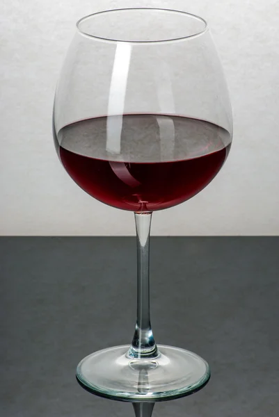 Ein mit Wein gefülltes Glas auf einem schwarzen Tisch — Stockfoto