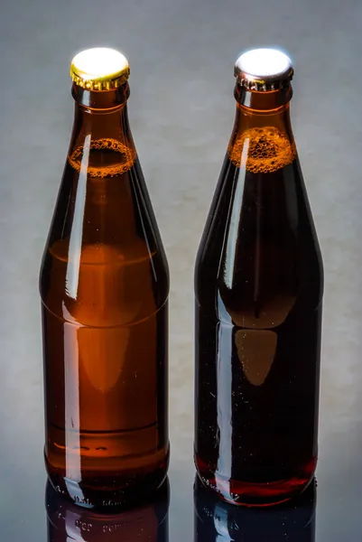 Duas garrafas de cerveja em uma superfície reflexiva — Fotografia de Stock