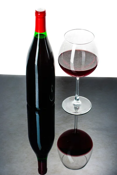 Vinflaska och ett glas fyllt med vin på en svart reflekterande s — Stockfoto