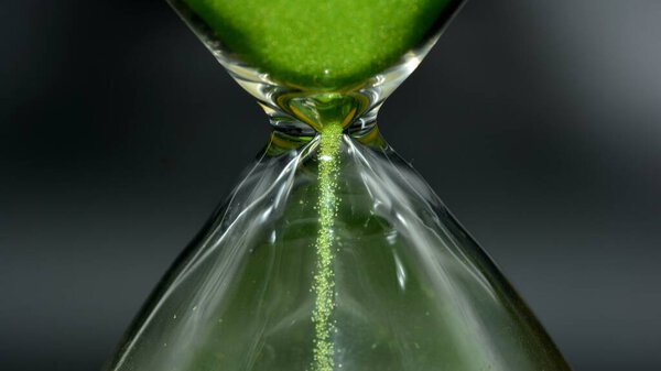 Detail of a green hourglass, with a black background
