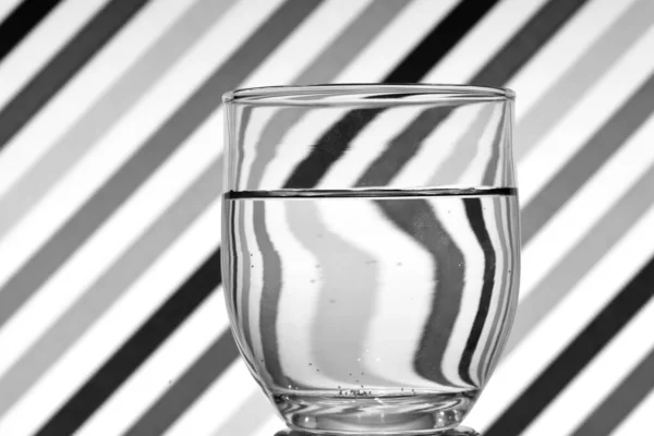 Optical illusion created by the refraction of light, black and white oblique lines reflected in a glass of water