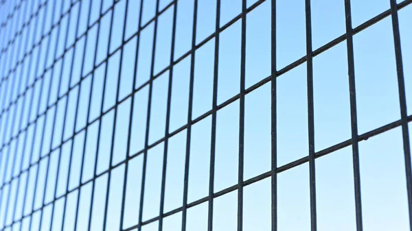 Detail of an iron fence or mesh with the blue sky in the background