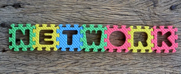 Jigsaw written network word on wood background — Stock Photo, Image