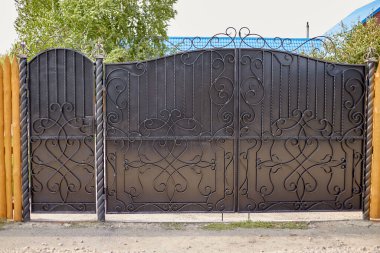 Çitin kenarlarında ahşap tahtalardan yapılmış bir deseni olan metal siyah kapı..