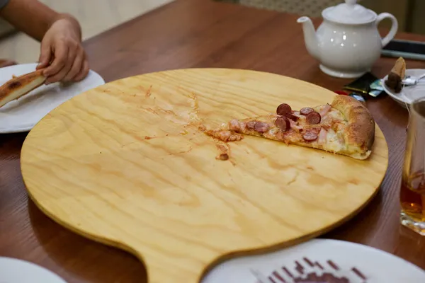 At the pizza-eating dinner, the last piece was left, a slice on a wooden tray.