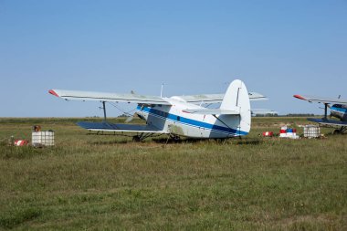 Mavi çizgili eski bir Sovyet uçağı havaalanındaki bir tarlada duruyor..