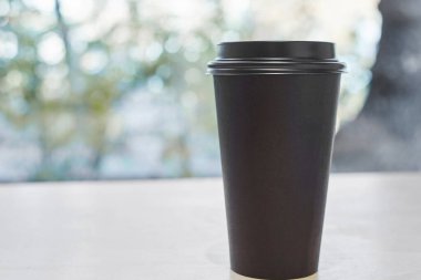 Tek kullanımlık siyah kahve fincanı, bir kafede masanın üzerinde duruyor.