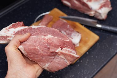 Aşçı elinde bir parça çiğ et, domuz eti ve yemek tutuyor..