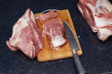 Siyah bir masada et kesiyor, aşçı yemek pişirmek için et kesiyor..