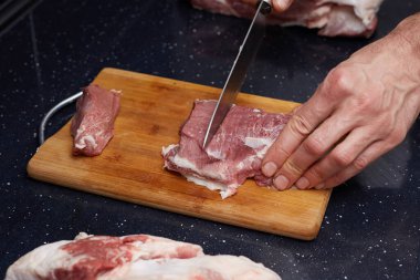Aşçı çiğ et keser. Et ve kemik ahşap bir kesme tahtasına serilmiştir..