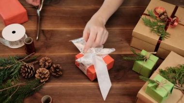 Noel hediyelerini paketlemek için beyaz kar tanesi kurdelesini kesmek için makas kullanın. Noel hediyesi paketleme.