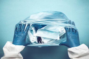Plastik bir çantada tıbbi maskeler kullanılmış. Kullandıktan sonra mavi maskeler. Kullanılan tıbbi maskeler.