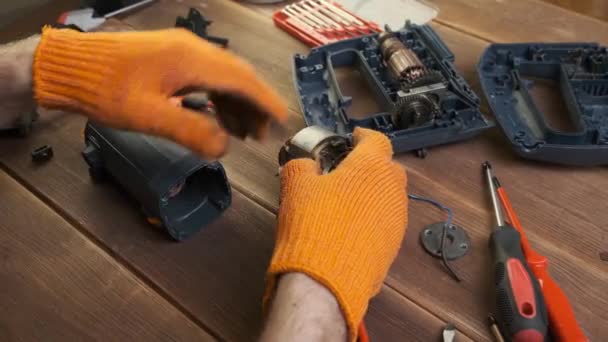 電動工具修理 修理工場の木製テーブルの上の電気機器や修理ツールの詳細 電気器具を修理するオレンジ色の手袋のフォアマンの手 — ストック動画