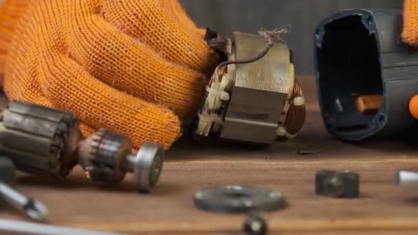 電動工具修理 修理工場の木製テーブルの上の電気機器や修理ツールの詳細 電気器具を修理するオレンジ色の手袋のフォアマンの手 — ストック動画