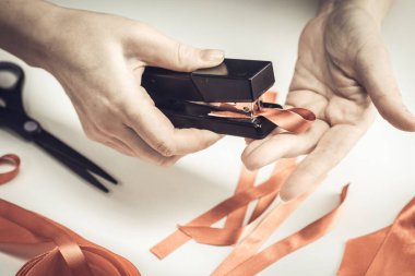 Sağlık ve tıp konsepti. AIDS farkındalığı. Kadın elleri kırmızı kurdele ve zımbayla kırmızı farkındalık kurdelesi yapar. Dünya Yardım Günü.