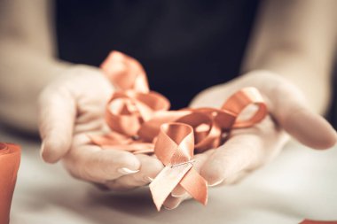 Sağlık ve tıp konsepti. AIDS farkındalığı. Kadın elleri kırmızı kurdele ve zımbayla kırmızı farkındalık kurdelesi yapar. Dünya Yardım Günü.