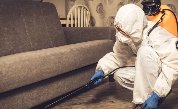 Deratizátor v pracovním oblečení rozstřikuje pesticidy stříkací pistolí. Boj proti hmyzu v bytech a domech. Disekce v areálu — Stock fotografie