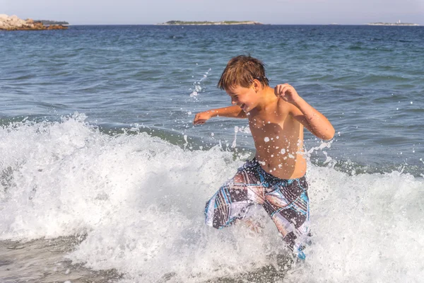 Boy running through the water at the beach — Stock Photo, Image