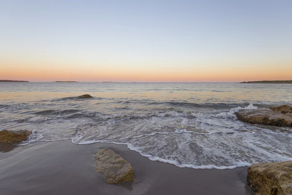 Pôr do sol paisagem marinha com rochas em primeiro plano — Fotografia de Stock