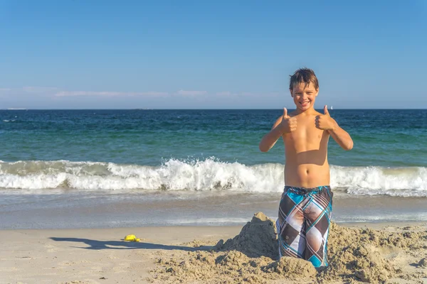 Boy with thumbs up at beach — Stock Photo, Image