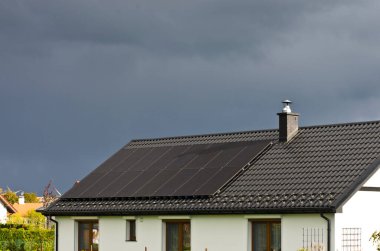 Bulutlu bir günde, birinci sınıf bir evin çatısındaki modern siyah hücre güneş panelleri.