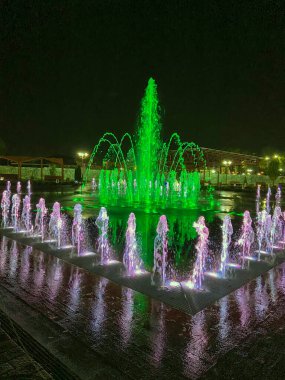 Parktaki çeşmenin gece manzarası. Geceleri halka açık bir parkta renkli fıskiyeler, uzun pozlar.