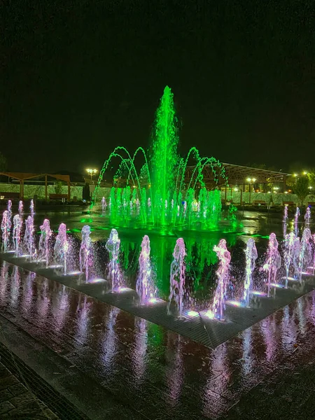 Parktaki çeşmenin gece manzarası. Geceleri halka açık bir parkta renkli fıskiyeler, uzun pozlar.