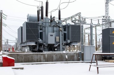 Karda kışın elektrik santralinde yüksek voltajlı elektrik trafosu..