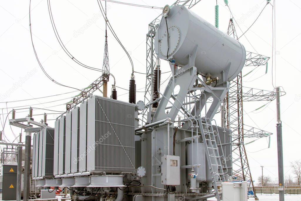 Power transformer at high voltage outdoor electrical substation in winter.