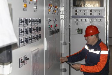 Sanayi üretiminde güç üretimi için kontrol paneli sistemini inceleyen teknisyen