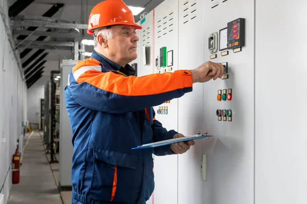 Bir elektrik mühendisi kontrol odasındaki elektrik sistemini kontrol eden kontrol panellerini inceliyor.