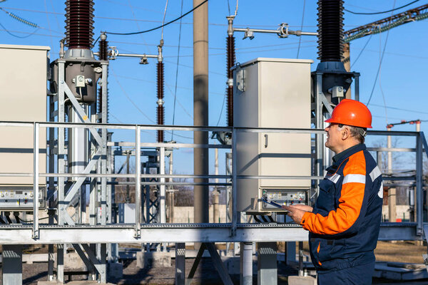 Power engineer inspects substation equipment. Energy. Industry.