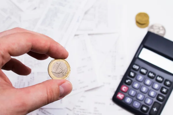 Hand hält Euromünze und Taschenrechner im Hintergrund — Stockfoto