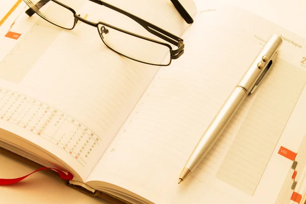 Opened organizer with glasses and pen — Stock Photo, Image