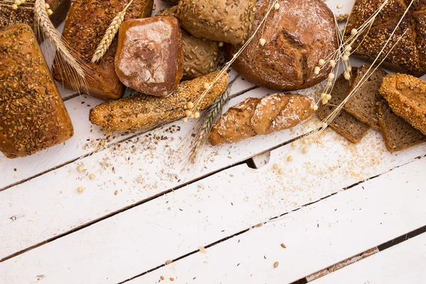 Different types of bread on white wooden board — Stock Photo, Image