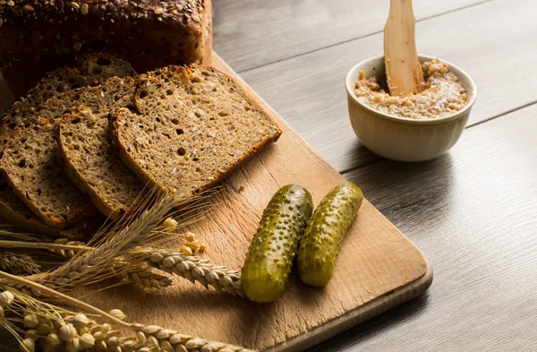 Bread lard and pickles on old wooden cutting board — Stock Photo, Image