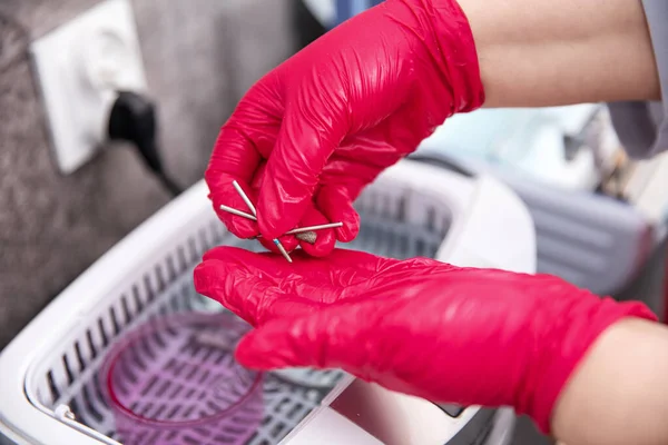 The beautician preparing tools for disinfection with a special liquid