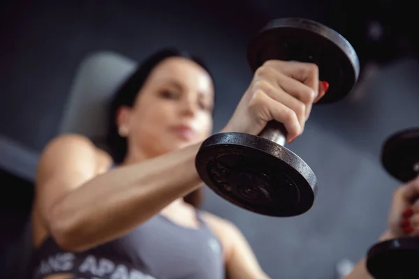 Dumbbells in hands of young fit brunette.