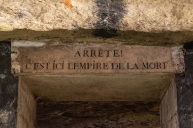 Paris, Fransa: Yazıt: Dur! Burası Paris 'in yeraltı mezarlarının girişindeki ölüm imparatorluğu. 285 km uzunluğundaki bir yeraltı taş ocağında dünyanın en büyük mezarlığı olan 6 milyondan fazla insanın kalıntıları bulunuyor.
