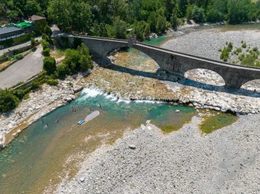 Hava görüntüsü. Kuraklık ve kuru nehirler. Bobbio köprüsü Trebbia nehri üzerinde, Piacenza, Emilia-Romagna. İtalya. 06-16-2022. Taşları ve bitkileri olan bir nehir yatağı. Buna kambur köprü denir, eski ya da şeytan köprüsü. Yüzer.
