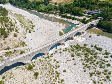 Hava görüntüsü. Kuraklık ve kuru nehirler. Bobbio köprüsü Trebbia nehri üzerinde, Piacenza, Emilia-Romagna. İtalya. 06-16-2022. Taşları ve bitkileri olan bir nehir yatağı. Buna kambur köprü denir, eski ya da şeytan köprüsü. Yüzer.