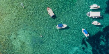 Şeffaf bir denize demirlenmiş yüzen teknelerin havadan görüntüsü. İyon Denizi 'nde rahatla. Banyo. Korfu adası, Limni plajı Glyko. Yunanistan