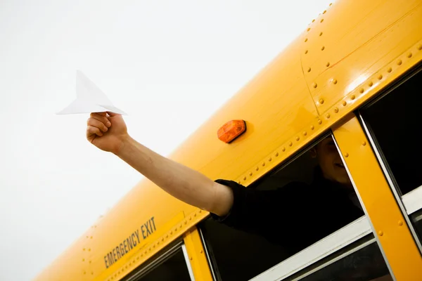 Schulbus: Junge hält Papierflugzeug aus Fenster — Stockfoto