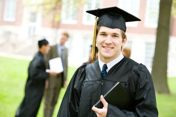 Graduação: Graduado inteligente com outros por trás — Fotografia de Stock